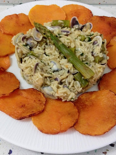Una foto de Arroz salteado con coquinas y espárragos con chips de calabaza frita