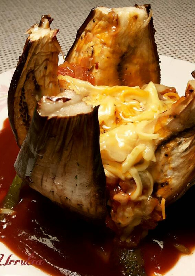 Una foto de Berenjena rellena al horno, con salsa de picadillo de tomate y queso