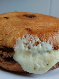 Una foto de Sándwich🥯de cebolla🧅y tocineta🥞 caramelizada🥓con queso🧀en pan de almojábana🥯