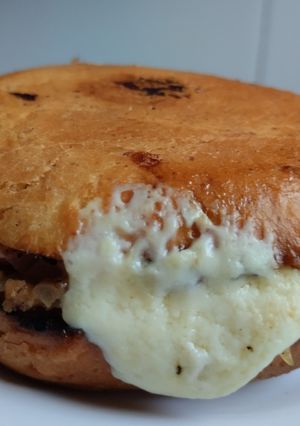 Una foto de Sándwich🥯de cebolla🧅y tocineta🥞 caramelizada🥓con queso🧀en pan de almojábana🥯