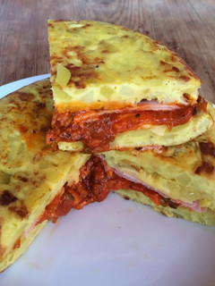 Una foto de Tortilla de patatas con jamón york y queso y salsa de tomate