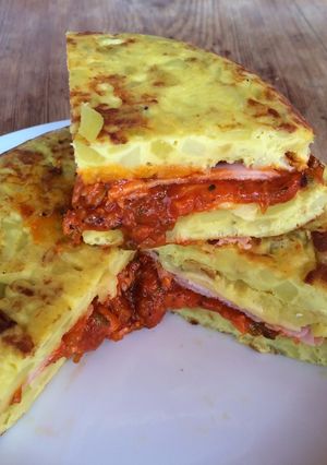 Una foto de Tortilla de patatas con jamón york y queso y salsa de tomate