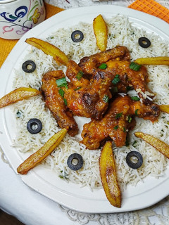 A picture of Buffalo hot wings with fried spring onions rice.
