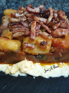 Una foto de Pisto y patatas panaderas con panceta, sobre omelette