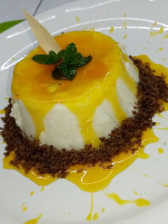 Una foto de Panna cotta de coco con coulis de flor de cempasúchil y mezcal