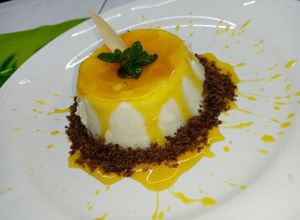 Una foto de Panna cotta de coco con coulis de flor de cempasúchil y mezcal