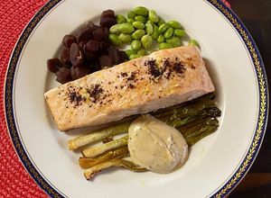 Une photo de Saumon au sumac, carottes violettes, edamames, oignons glacés et sauce tahini