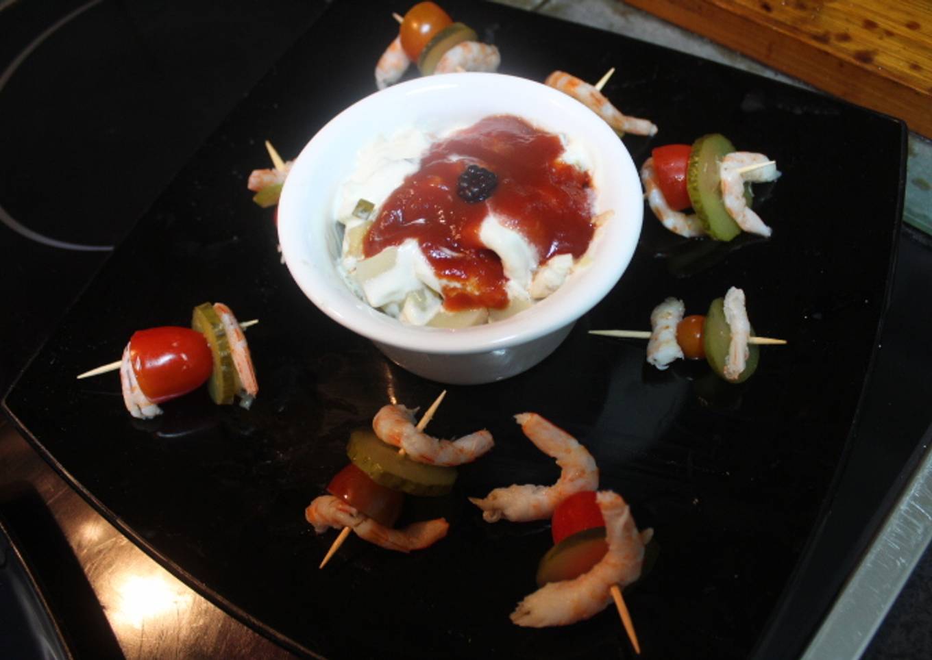 Ensalada de filetes de arenque acompañada de pinchos de gambas