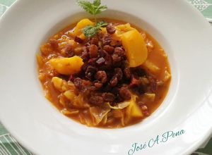 Una foto de Col o repollo cocinada: con patatas cocidas, jamón ibérico y pasas