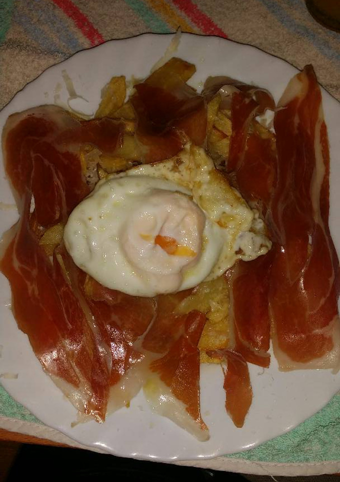 Una foto de Huevo roto con patata, jamon y queso