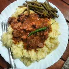 A picture of Stewed beef with creamy mashed potatoes served with sauteed buttery string beans.