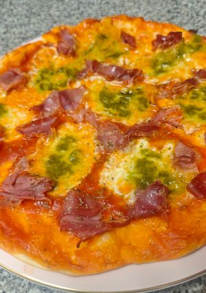 Una foto de Pizza casera de mozzarella di búfala jamón y pesto