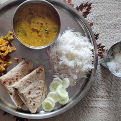 A picture of Gujarati khatti meethi dal with rice roti alu patta gobhi gajar.