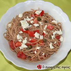 A picture of Spaghetti with raw tomato and olives.