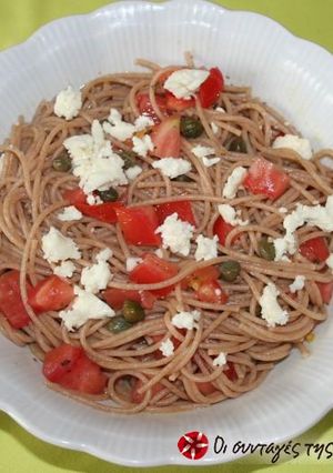A picture of Spaghetti with raw tomato and olives.