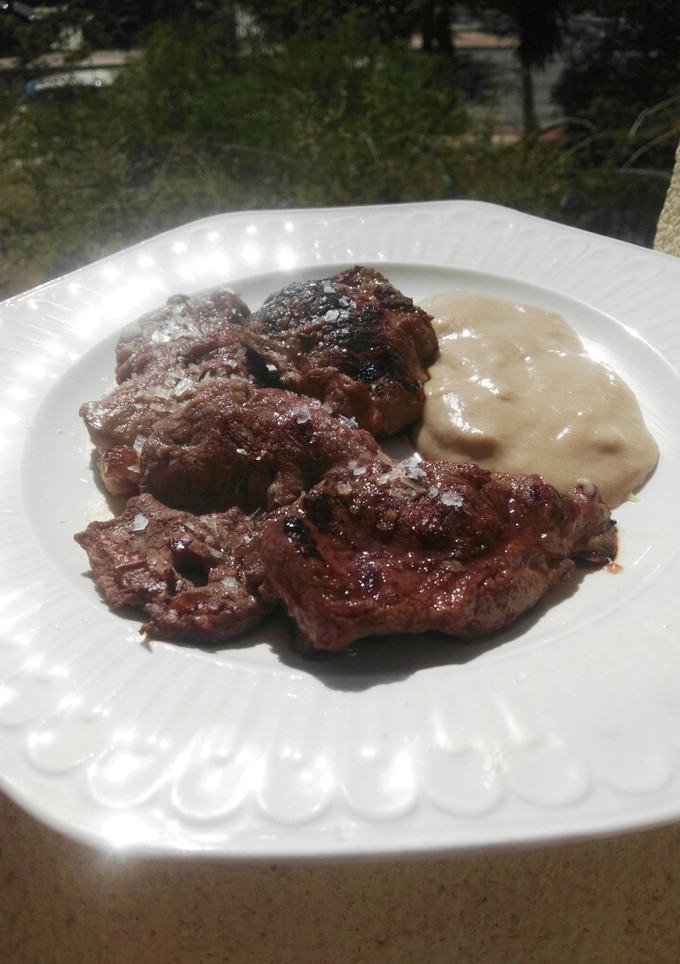Una foto de Carrilleras a la plancha con puré de patatas y ajo negro