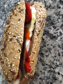 Una foto de Bocadillo con tomate, queso fresco, pimientos del piquillo y anchoas