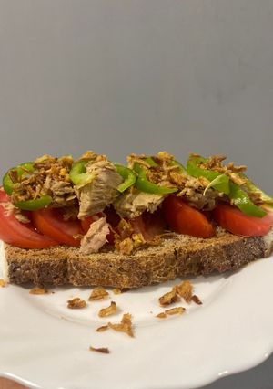 Una foto de Tostada de tomate, bonito, pimiento verde, cebolla crujiente y aove
