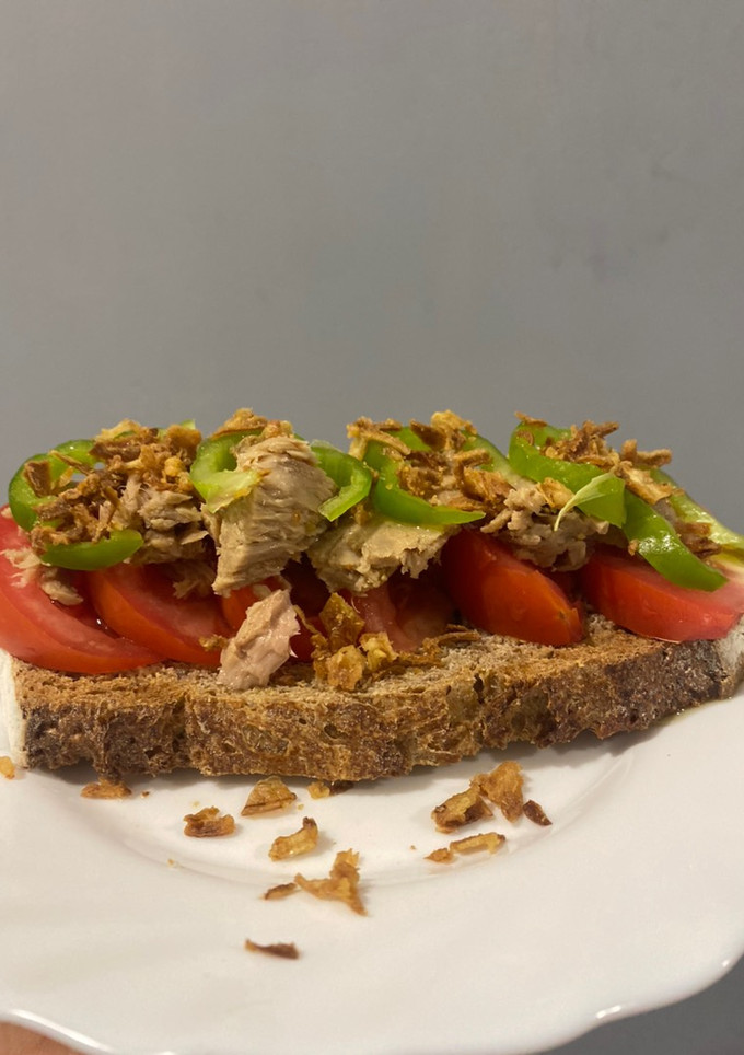 Una foto de Tostada de tomate, bonito, pimiento verde, cebolla crujiente y aove