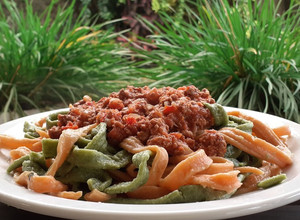Una foto de Fideos caseros de morrón y de espinaca con salsa bolognesa