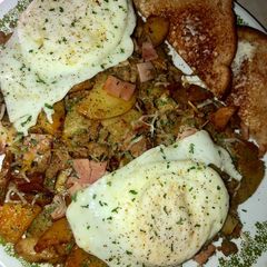 A picture of Sausage, ham and fried potato skillet topped with eggs.