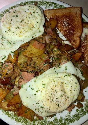 A picture of Sausage, ham and fried potato skillet topped with eggs.