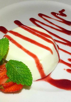 Una foto de Panna cotta con coulis de fresa y frambuesa
