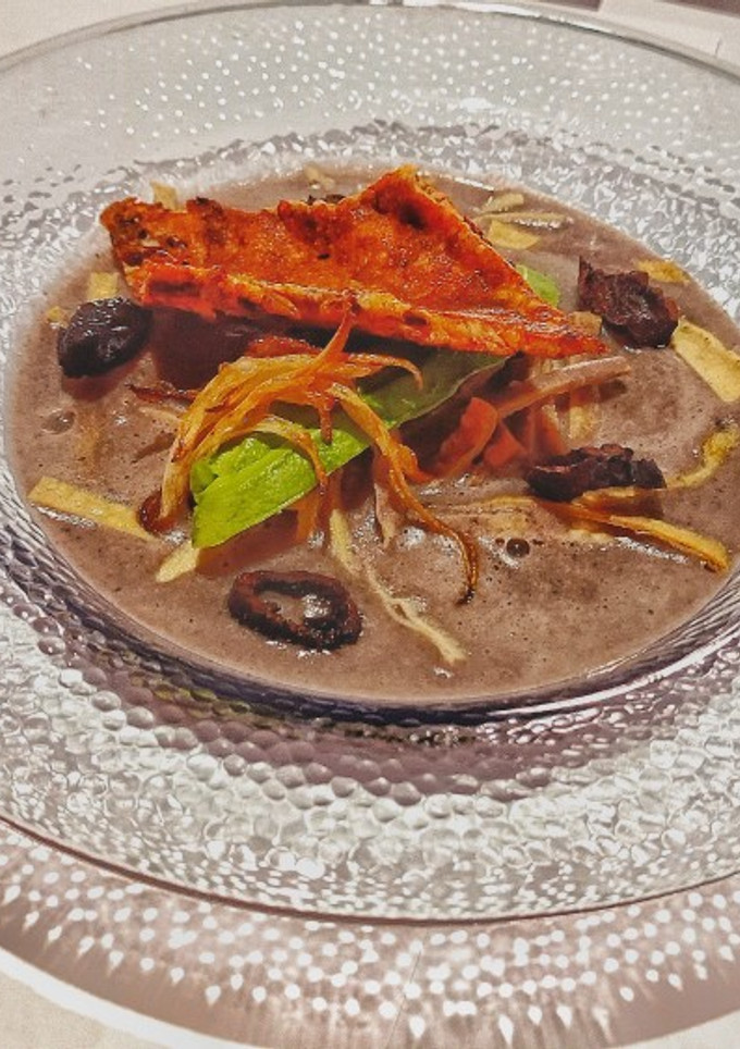 Una foto de Crema de frijol y costra de quesillo con chapulines