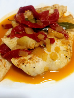 Una foto de Filetes de merluza con pimientos de piquillo y ajos confitados