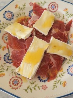 Una foto de Carpaccio de higos, un buen jamón ibérico, queso brie y miel