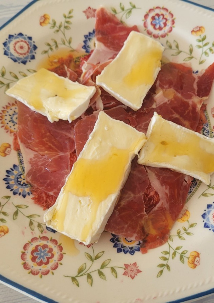 Una foto de Carpaccio de higos, un buen jamón ibérico, queso brie y miel