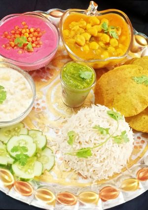 A picture of Punjabi Thali / Choley Puri, Boondi Raita, Beetroot Raita, Rice.