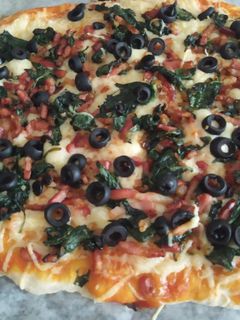 Una foto de Pizza de espinacas, cebolla, bacon y aceitunas negras