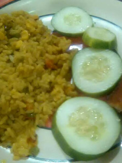 A picture of Garnished jellof rice with chicken and cucumber.
