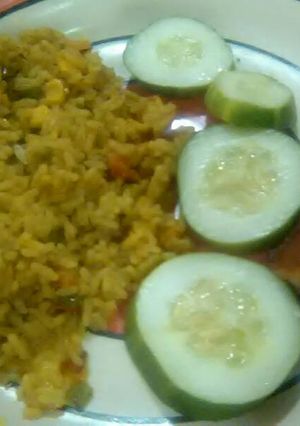 A picture of Garnished jellof rice with chicken and cucumber.
