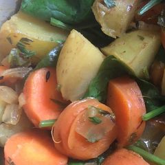 A picture of Vegetable curry with carrots, carrot tops, potatoes and spinach.