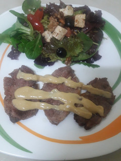 Una foto de Presa de cerdo en salsa de mostaza y miel con ensalada de rúcula y queso feta