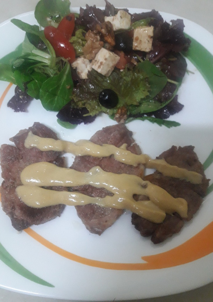 Una foto de Presa de cerdo en salsa de mostaza y miel con ensalada de rúcula y queso feta