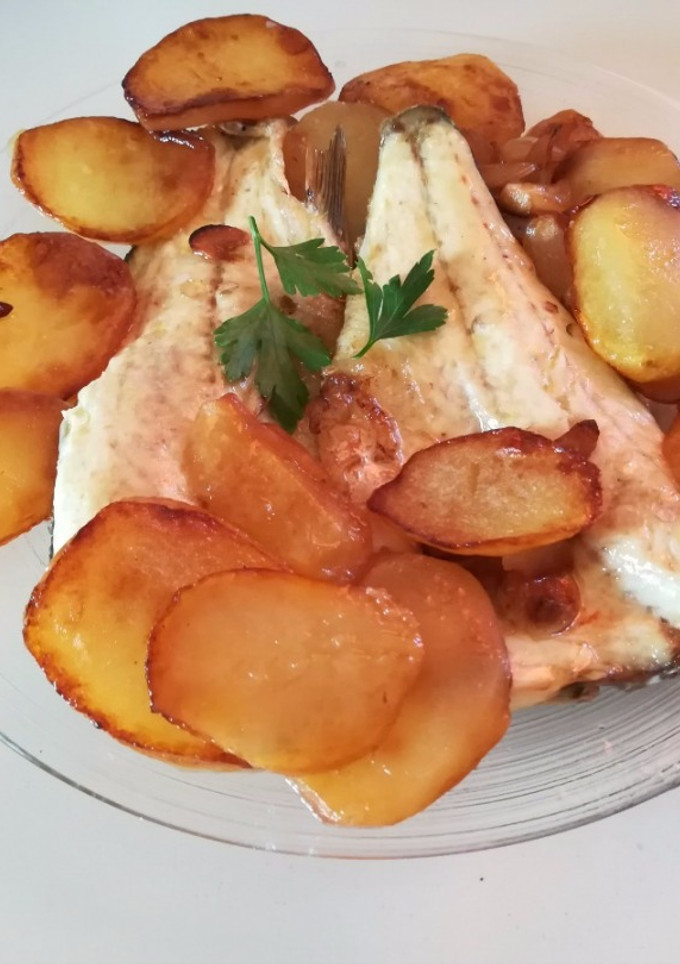 Una foto de Lubina al horno con patatas panadera