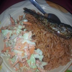 A picture of Jollof rice with fried fish and coleslaw.