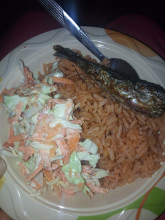 A picture of Jollof rice with fried fish and coleslaw.