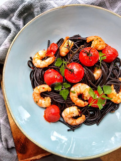 A picture of Squid Ink Spaghetti With King Prawns, Vine Tomatoes & Chilli.
