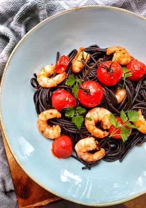A picture of Squid Ink Spaghetti With King Prawns, Vine Tomatoes & Chilli.