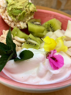 Una foto de Almuerzo o desayuno saludable: bowl de yogur con fruta y flores