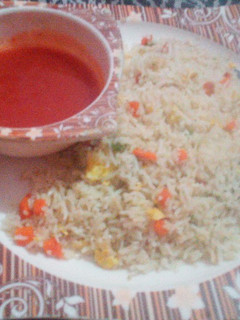 A picture of Egg fried rice with Red sauce.