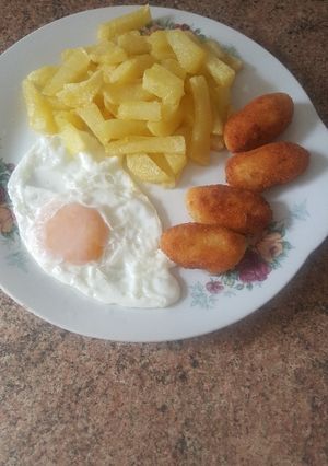Una foto de Patatas fritas con huevo frito y croquetas