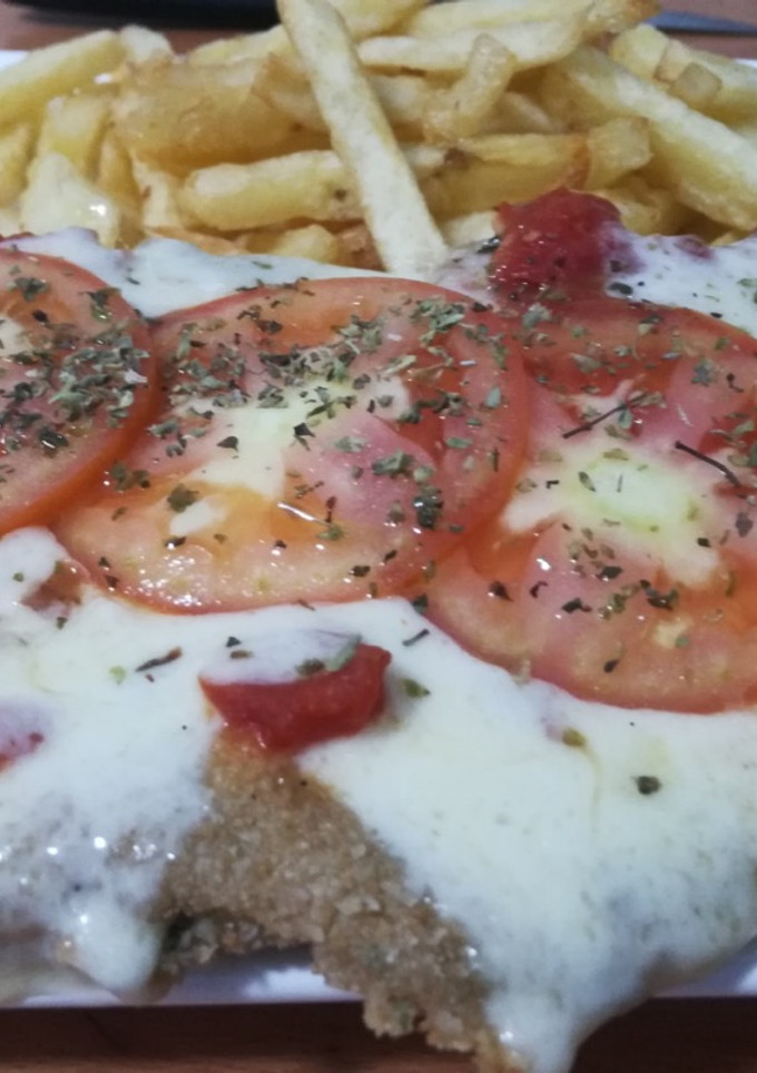 Una foto de Milanesa a la Napolitana con papas fritas