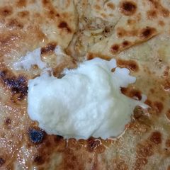 A picture of Potato parantha with white butter.