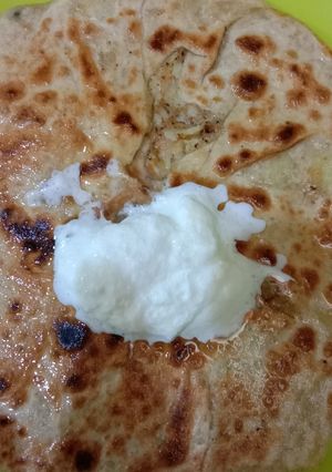 A picture of Potato parantha with white butter.