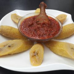 A picture of Boiled plantain with tomato sauce and fried chicken.